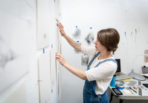 Student putting art up on the wall